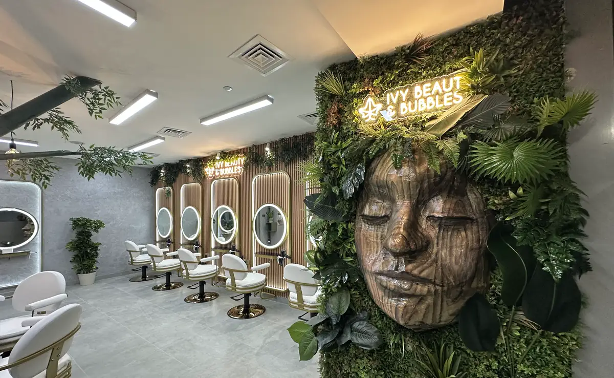 IVY Beauty & Bubbles hair salon in Doha with the illuminated IVY neon sign, a living plant wall and arched mirrors